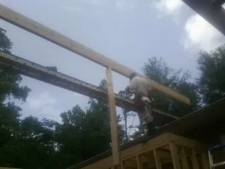 Carpenter setting a ridge beam over a new addition frame — Ice Dam Removal by Roofing Brothers in Bumpass