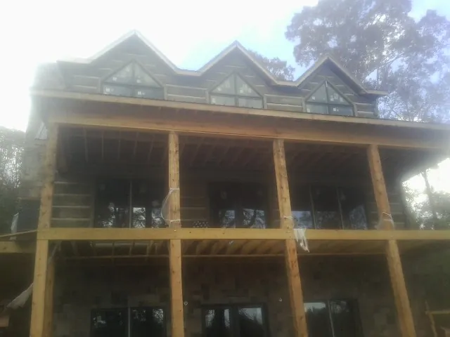 Dormers and porch framing on a large log home under construction — Roof Coating work by our crew in Bumpass