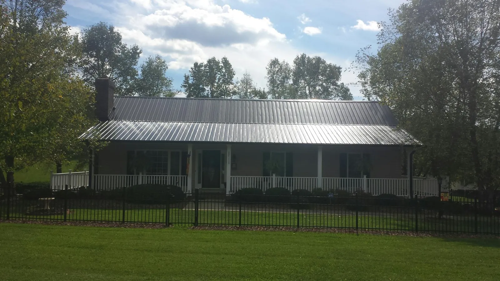 Gray metal roof on a brick ranch with a full width front porch — Gutter Guard Installation work by our crew in Bumpass