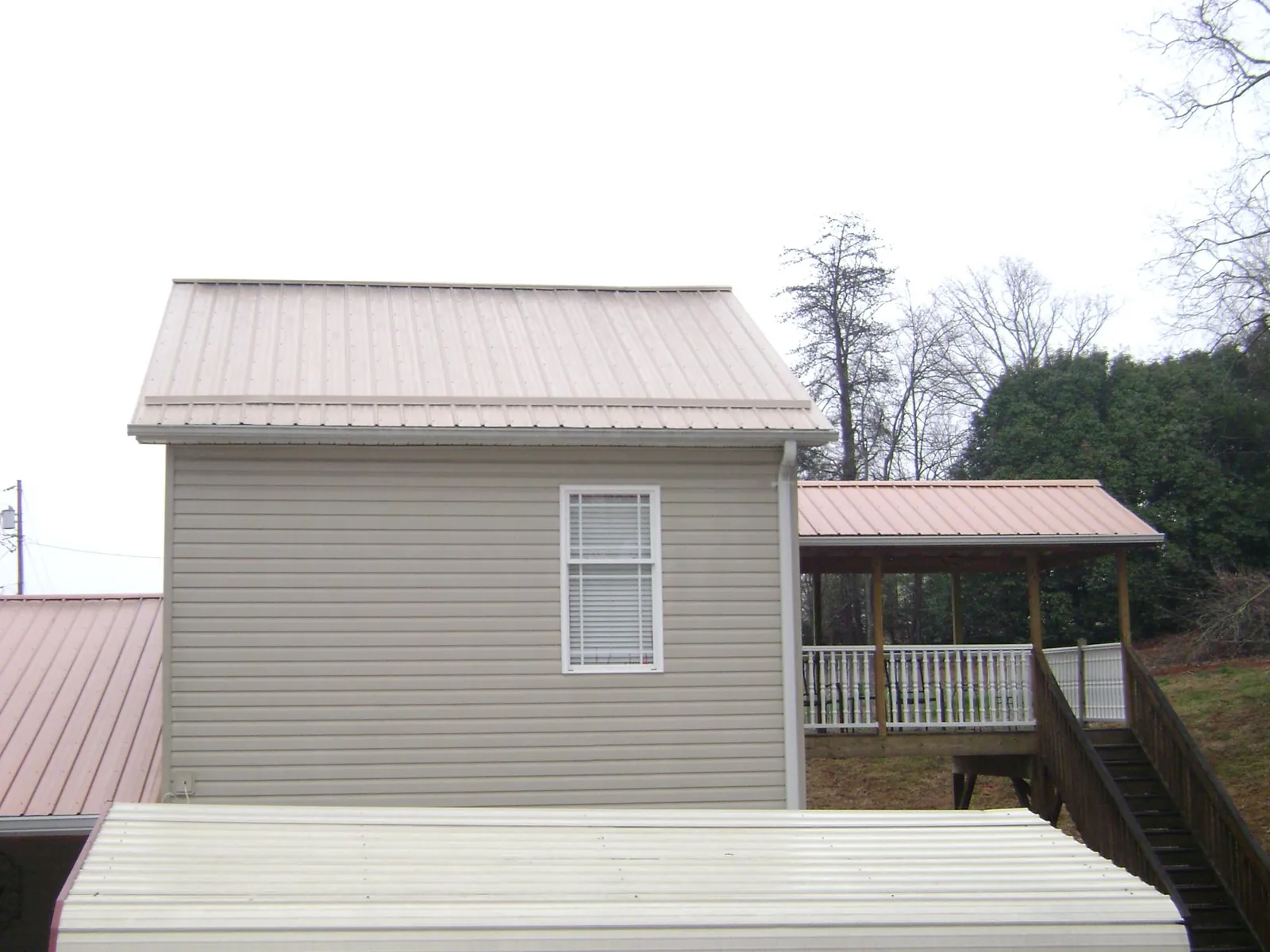 Tan metal roofs on a two story addition and attached porch, from a Roof Replacement job in Bumpass
